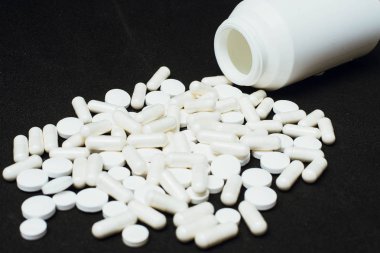 Siyah arka planda beyaz haplar. Sağlık, ilaç ve tedavi kavramı