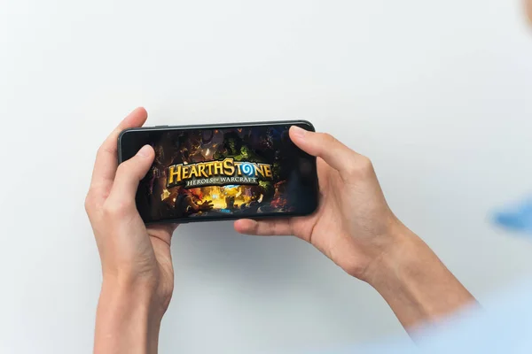 Samara, Russia -07, 29, 2019: A young guy plays a HearthStone game on Iphone 8 Plus. Teenage boy holding a phone in his hands with a game Hearth Stone on a white background — Stock Photo, Image