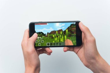 Samara, Rusya -07, 29, 2019: Iphone 8 Plus'ta minecraft oyunu oynayan genç bir adam. Genç çocuk beyaz bir arka plan üzerinde bir oyun minecraft ile elinde bir telefon tutarak