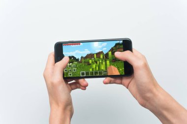 Samara, Rusya -07, 29, 2019: Iphone 8 Plus'ta minecraft oyunu oynayan genç bir adam. Genç çocuk beyaz bir arka plan üzerinde bir oyun minecraft ile elinde bir telefon tutarak