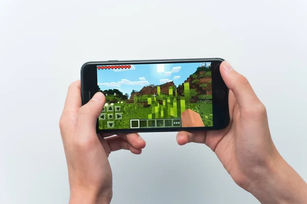 Samara, Russia -07, 29, 2019: A young guy playing minecraft game on Iphone 8 Plus. Teenage boy holding a phone in his hands with a game minecraft on a white background — Stock Photo, Image