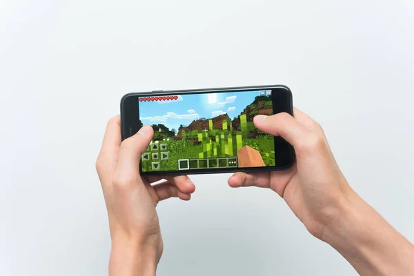 Samara, Russia -07, 29, 2019: A young guy playing minecraft game on Iphone 8 Plus. Teenage boy holding a phone in his hands with a game minecraft on a white background — Stock Photo, Image