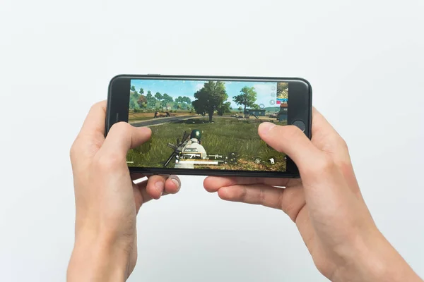 Samara, Russia -07, 29, 2019: A young guy plays a PUBG game on Iphone 8 Plus. Teenage boy holding a phone in his hands with a game PlayerUnknown's Battlegrounds on a white background — Stock Photo, Image