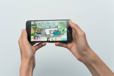 Samara, Rusya -07, 29, 2019: Genç bir adam Iphone 8 Plus bir Sims oyunu oynar. Genç çocuk beyaz bir arka plan üzerinde bir oyun Sims mobil ile elinde bir telefon tutarak
