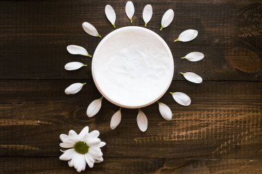 Cilt bakımı. Güneş cilt bakımı kavramı. Güneşahşap bir masa üzerinde vücut ve yüz için beyaz maske. Güneş şeklinde yaprakları.