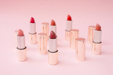 Pembe pastel arka plan üzerinde pembe standı farklı tonlarında birçok lüks altın rujlar