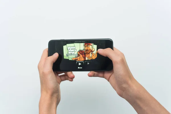 Samara, Russia -07, 29, 2019: Un joven jugando a GTA en Iphone 8 Plus. Adolescente sosteniendo un teléfono en sus manos con un juego Grand Theft Auto: San Andreas sobre un fondo blanco — Foto de Stock