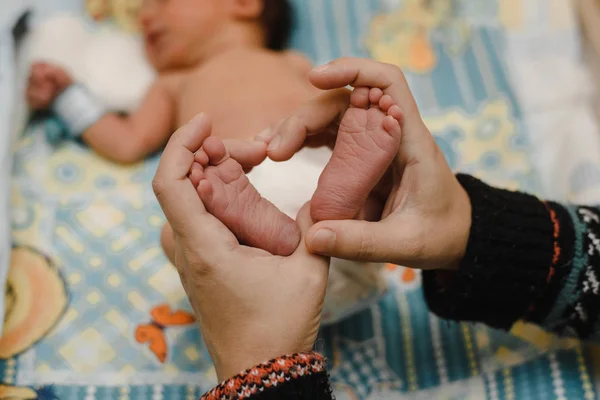 Füße eines neugeborenen Babys in den Händen der Eltern. das Konzept von Liebe, gesunder Geburt und glücklichen jungen Eltern — Stockfoto