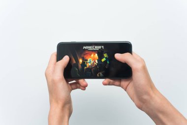 Samara, Rusya -07, 29, 2019: Iphone 8 Plus'ta minecraft oyunu oynayan genç bir adam. Genç çocuk beyaz bir arka plan üzerinde bir oyun minecraft ile elinde bir telefon tutarak