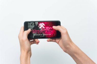 Samara, Rusya -07, 29, 2019: Iphone 8 Plus'ta Plague Inc: Evolved oyunu oynayan genç bir adam. Genç çocuk beyaz bir arka plan üzerinde bir oyun Plague Inc ile elinde bir telefon tutarak