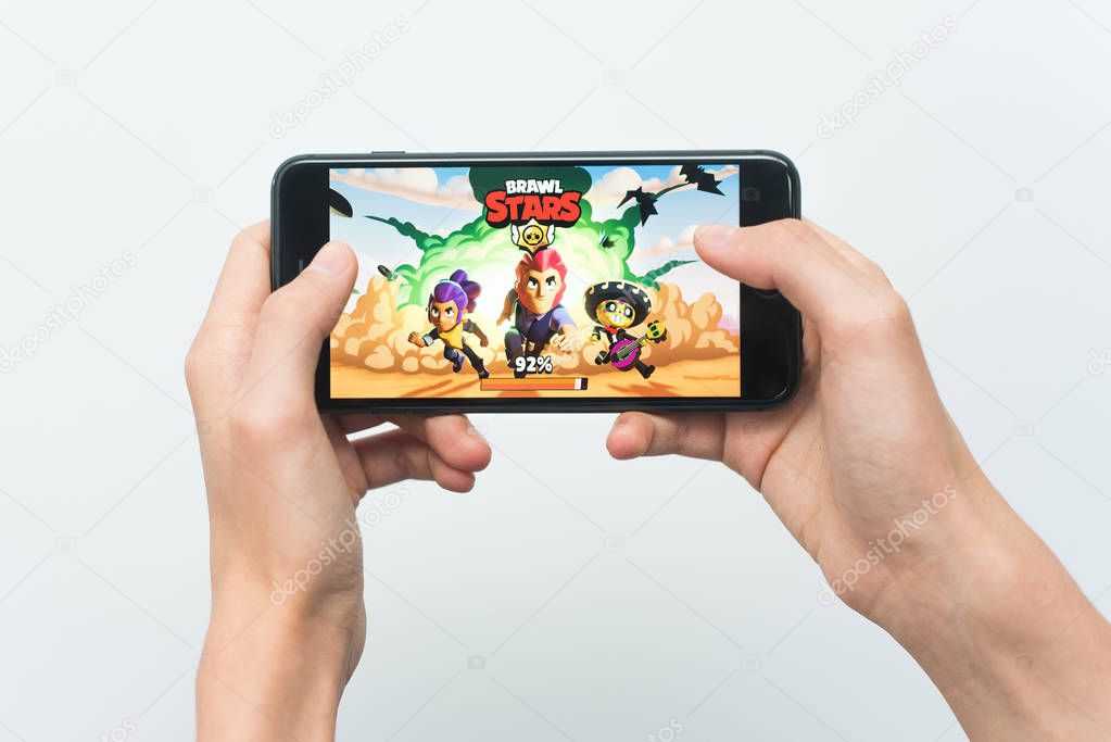 Samara, Russia -07, 29, 2019: A young guy playing brawl stars game on Iphone 8 Plus. Teenage boy holding a phone in his hands with a game Brawl Stars on a white background