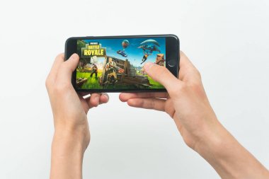 Samara, Rusya -07, 29, 2019: Iphone 8 Plus'ta Fortnite oyunu oynayan genç bir adam. Genç çocuk beyaz bir arka plan üzerinde bir oyun Fortnite savaş royale elinde bir telefon tutarak