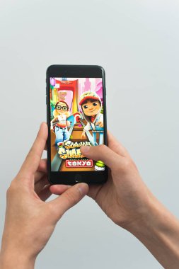 Samara, Rusya -07, 29, 2019: Genç bir adam Iphone 8 Plus'ta metrosörfü oynuyor. Genç çocuk beyaz bir arka plan üzerinde bir oyun metro sörfçü ile elinde bir telefon tutarak