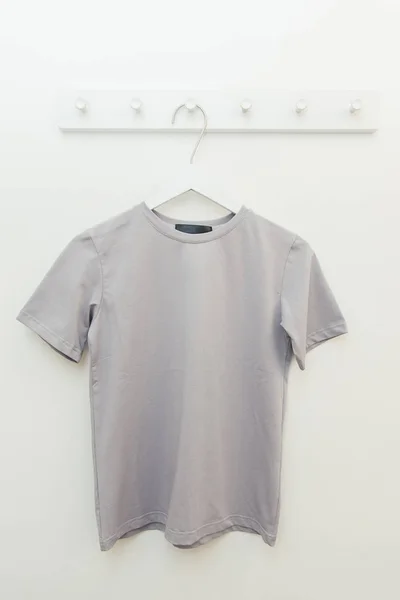gray basic t-shirt in a fitting room on a hanger