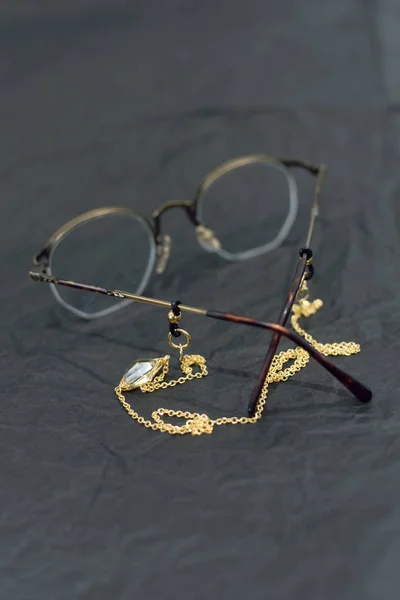 Elegante cadena de oro con una gema transparente en las gafas. tendencia en las cadenas de puntos. Gafas vintage negro, papel pergamino arrugado — Foto de Stock