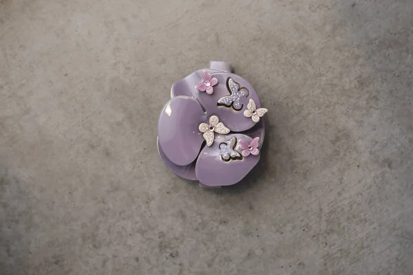 Schöne lila Plastikbarrette mit Schmetterlingen auf einem schönen grauen Grunge-Hintergrund — Stockfoto