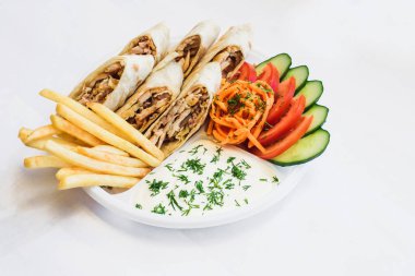 Gölgeli bir tabakta izole shawarma. Tavuk eti, domates, Kore havuç, patates kızartması, pide salatalık yapılan oryantal gıda