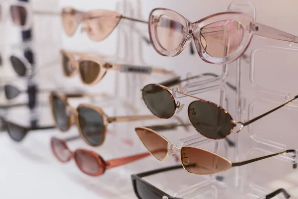 Stojak ze stylowymi, modnymi plastikowymi okularami. Sprzedaż detaliczna stylowych okularów — Zdjęcie stockowe