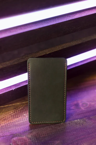 Leather phone case on a wooden background in neon light