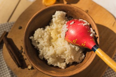 tereyağı ile bir çömlek içinde pirinç lapası. Tahta kaşıkla Rustik tarzı. Ahşap bir masada süt lapası