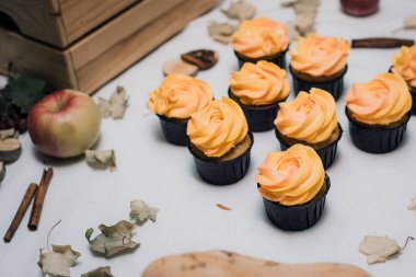 Sonbahar ölü yaprakları, kabak ve elma ile hafif bir arka plan üzerinde Sonbahar sarı ve turuncu cupcakes. Çocuklar için krem ile Sonbahar tatlılar. Sonbahar arka planda Havuç cupcakes.