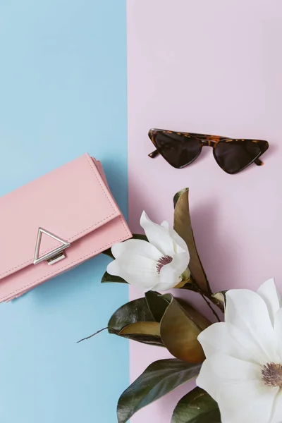 Vista superior y concepto de moda femenina, minimalismo. Gafas y bolso rosa sobre fondo rosa y azul . — Foto de Stock