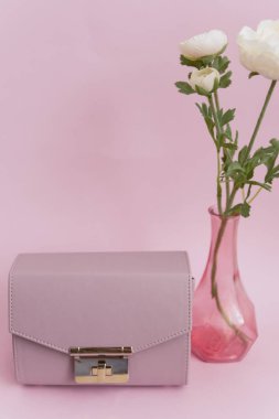 Kadın çantası ve pastel arka plan üzerinde bir vazo parlak çiçekler. Ofis moda konseptine geri dön.