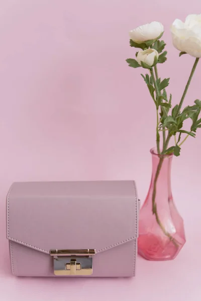 Damenhandtasche und helle Blumen in einer Vase auf pastellfarbenem Hintergrund. zurück zum Büromodekonzept. — Stockfoto