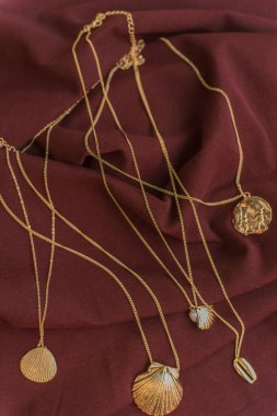 saten bordo arka plan üzerinde altın kolye. Kabukları ve sikkeile Altın takı.