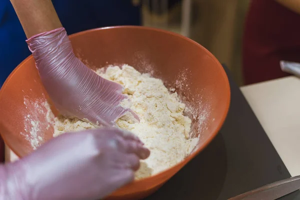 girl kneads dough made from flour and butter. A cook in gloves prevents flour from making dough