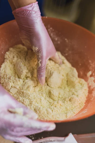 Menina amassa massa feita de farinha e manteiga. Um cozinheiro em luvas evita que a farinha faça massa — Fotografia de Stock