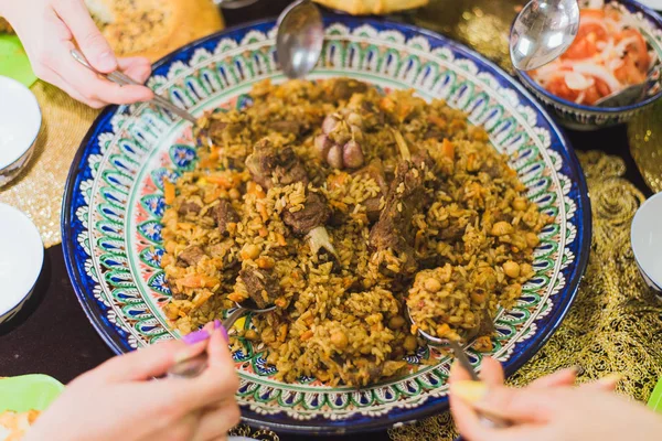 many people eat pilaf from the same plate. national uzbek dish.