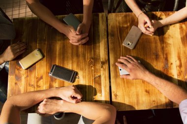 İnsanlar masada iletişim kuruyor. En iyi görüntü, farklı insanların telefonları. İletişim ve akıllı telefonlar ile insanların yerine sosyal sorun.