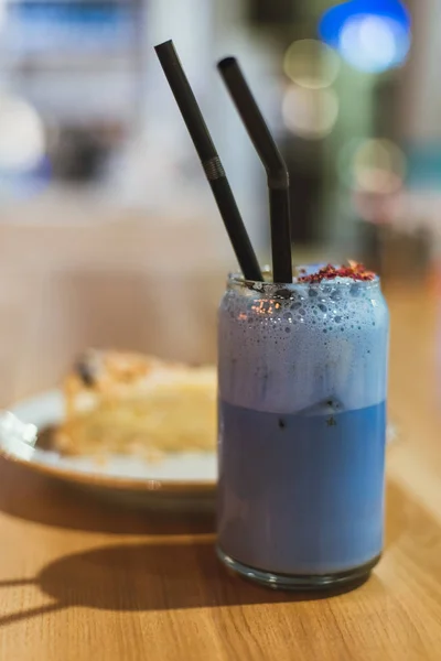 A drink from blue matches in a coffee shop. Healthy and proper expensive Chinese tea with a slice of cake on a wooden table. Lifestyle photo