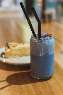 A drink from blue matches in a coffee shop. Healthy and proper expensive Chinese tea with a slice of cake on a wooden table. Lifestyle photo clipart