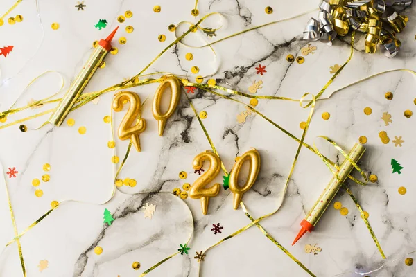 The concept of the new 2020 and Christmas. Candles in the shape of numbers 2020 as a symbol of the new year next to christmas shaped sparkler candles fountain on a marble table. top view, flat lay — Stock Photo, Image