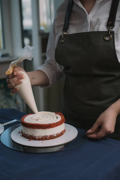 Confeiteiro espreme o creme no bolo. Menina fazendo um bolo — Fotografia de Stock