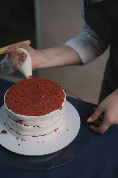 Confeiteiro espreme o creme no bolo. Menina fazendo um bolo — Fotografia de Stock