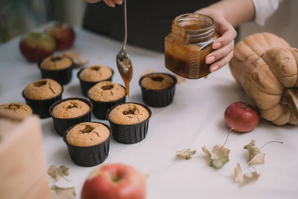 O padeiro cria cupcakes em moldes. Biscoitos de enchimento com caramelo líquido caseiro — Fotografia de Stock