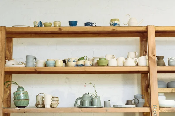 Ceramiche fatte a mano nel laboratorio di un vasaio. Argilla piatti, tazze e teiere sugli scaffali nello studio laboratorio — Foto Stock