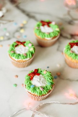 Yeni yıl tatlıları mermer bir masada. Makarna ve kremayla süslenmiş Noel kekleri.