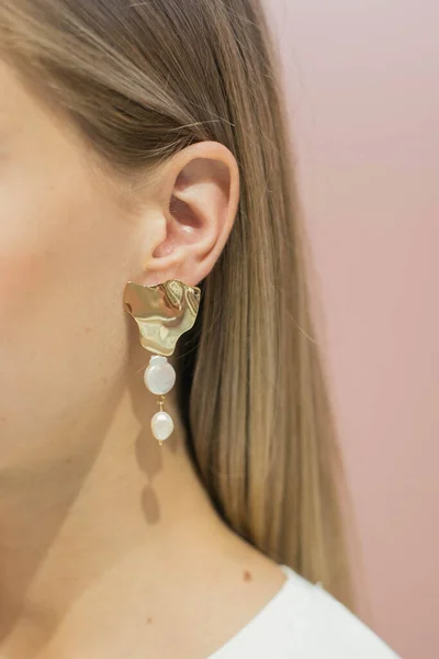 Brincos longos com pérolas e um pingente de ouro na orelha de uma menina com cabelo loiro — Fotografia de Stock