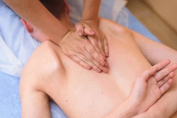 Masseur wrinkles back to client. Back massage for a young man — Stock Photo, Image