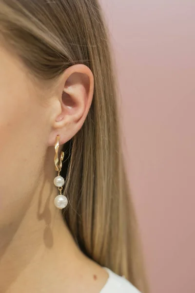 Серьги - кольца с жемчужными бусами на ушах блондинки на розовом фоне. Close view — стоковое фото