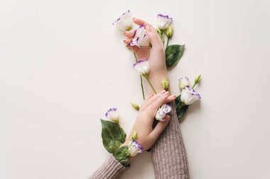 Beyaz masada narin eller ve bahar çiçekleri var. Cilt bakımı kavramı. El derisi bakımı için doğal kozmetik ürünleri, ellerdeki kırışıklıkları azaltmak için bir araç, nemlendirici. Doğal çiçek.