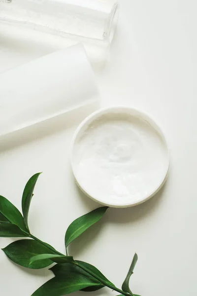 Means for skin care, rejuvenation and hydration of the face. Cream, micellar water and moisturizing lotion on a white background with a branch of green . The philosophy of self care and skin care — 스톡 사진