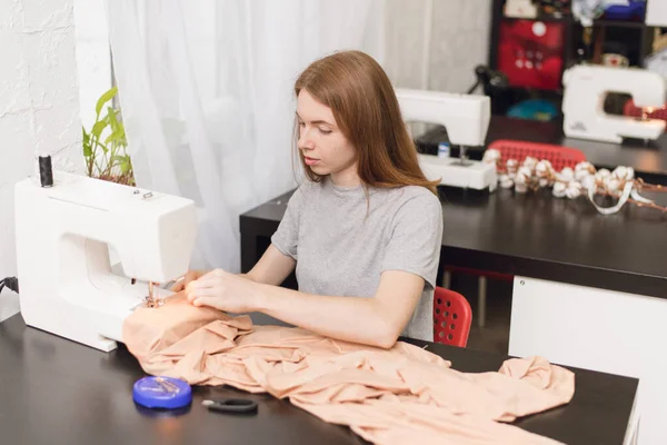 Couture à l'usine travaillant sur une machine à coudre. La fille a sa propre petite entreprise dans la couture de vêtements. La fille coud à une machine à coudre — Photo