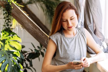 Sevimli bir kız, pencere kenarında bekleyen akrabaları ve arkadaşlarıyla video bağlantısıyla iletişim kuruyor. Bir kadın internette bir şey izliyor..