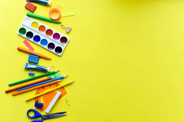 Material escolar artigos de papelaria em um fundo amarelo. Vista de cima — Fotografia de Stock