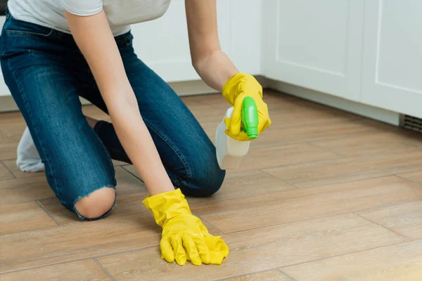 Uma rapariga está a lavar um chão com luvas amarelas. Uma menina está limpando um quarto com detergentes — Fotografia de Stock